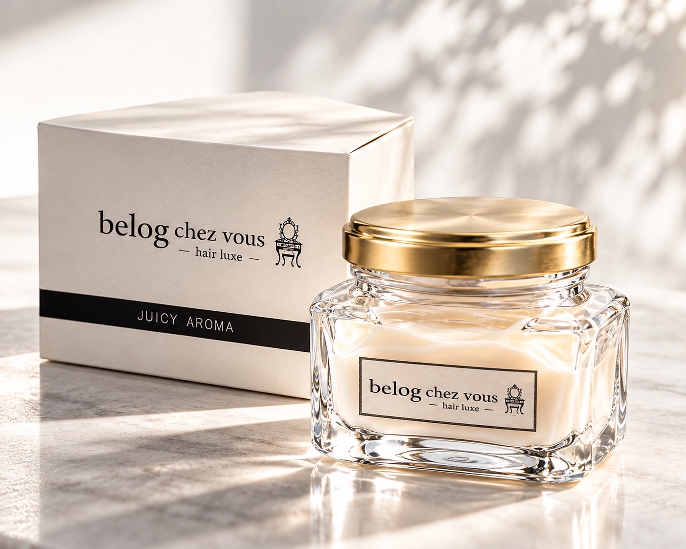 アイボリーの箱と並ぶ、ゴールドの蓋とアイボリーのクリームのヘアクリーム(belog chez vous ― hair luxe ―、JUICY AROMA)